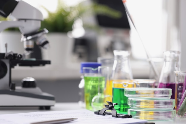 Liquido multicolore del microscopio in provette e carte sulla tavola nella ricerca di laboratorio in