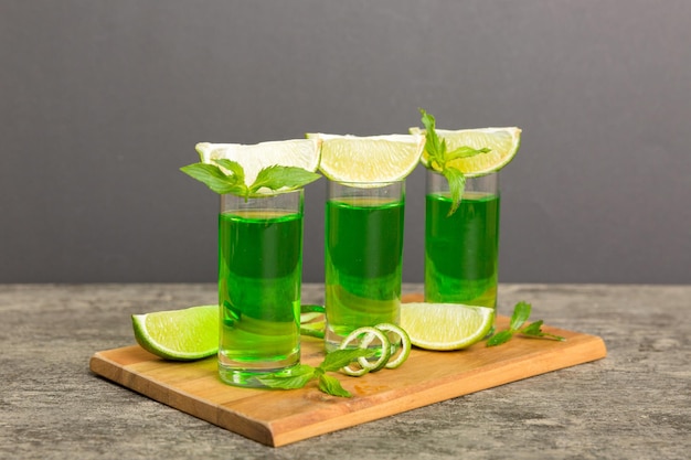 Liquore alla menta dolce e rinfrescante con ghiaccio e foglie di menta sullo sfondo del tavolo Scatti con fetta di lime e menta piatta