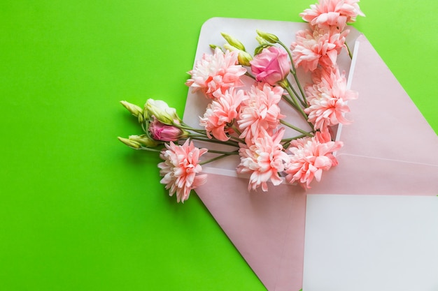 lisianthus rosa e crisantemi in busta su sfondo verde. festa della mamma, invito a nozze.