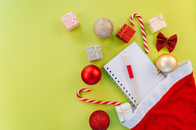 Lista dei desideri di Natale. Composizione di Natale. Casella attuale, caramelle di Natale, decorazioni festive rosse su fondo verde. Copia spazio.