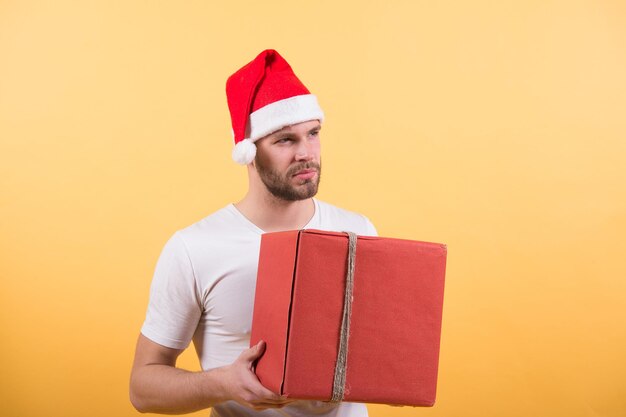 Lista dei desideri. Uomo bello indossare cappello da Babbo Natale tenere confezione regalo. Regalo di Natale della stretta dei pantaloni a vita bassa. Fai un regalo diffuso felicità. Congratulazioni concetto. Auguri di Natale. Servizio di consegna. Professione di corriere.