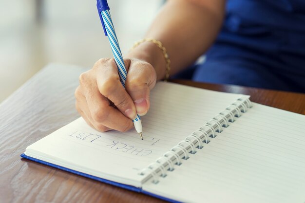 Lista di controllo di scrittura della mano della donna sul taccuino, concetto di pianificazione.
