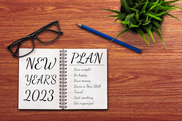 Lista di obiettivi e piani di risoluzione per il nuovo anno 2023 Scrivania d'ufficio aziendale con quaderno scritto sull'elenco dei piani di obiettivi e risoluzioni per il nuovo anni Impostazione del concetto di cambiamento e determinazione