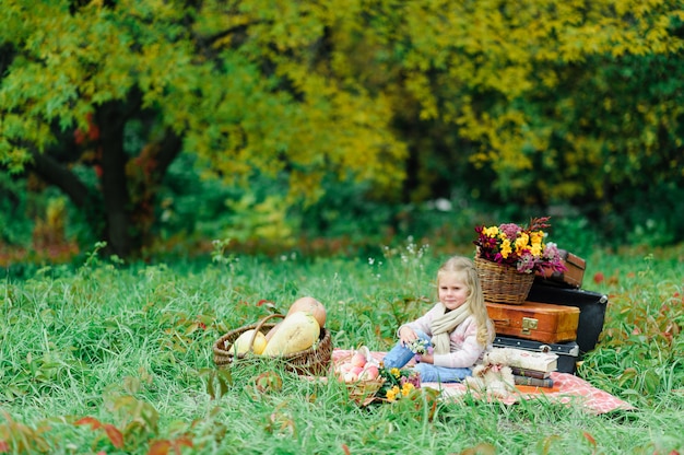 Litlle ragazza seduta su una coperta sull'erba