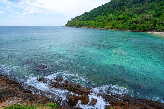 Litorale roccioso sotto il cielo azzurro e limpido con nuvole sullo sfondo della superficie del mare Bellissimo mare e piccola isola di Phuket in Thailandia.