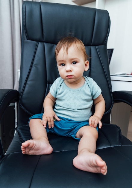 Little baby boss Bambino seduto in una sedia da ufficio in pelle