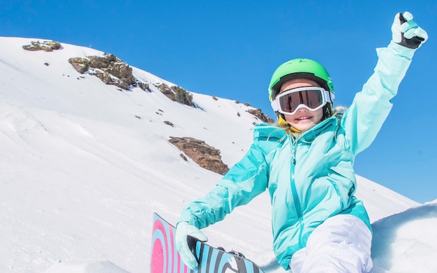 Little Cute Girl Snowboard presso la stazione sciistica nella soleggiata giornata invernale.