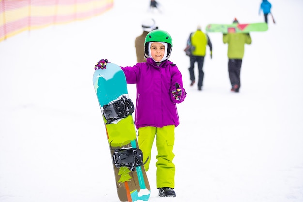 Little Cute Girl Snowboard presso la stazione sciistica nella soleggiata giornata invernale.