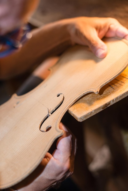 Liutaio che lavora e taglia i fori nel piano di un tavolo di violino