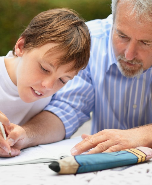 Lo aiuta a fare i compiti Inquadratura di un padre che aiuta il figlio a fare i compiti