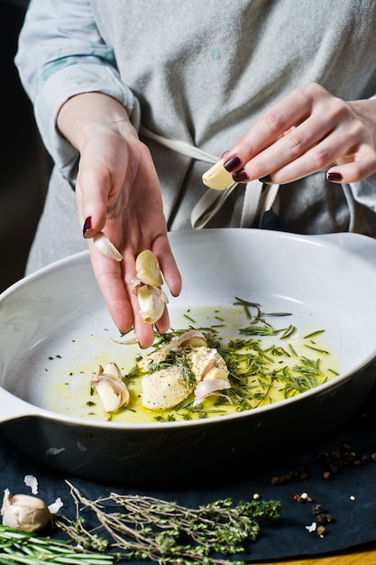 Lo chef aggiunge l&#39;aglio alla teglia. Il concetto di cucinare patate al forno.