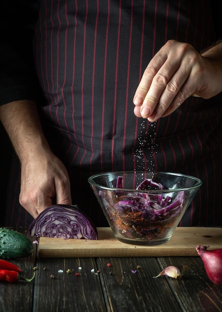 Lo chef aggiunge sale a un'insalata di cavolo rosso