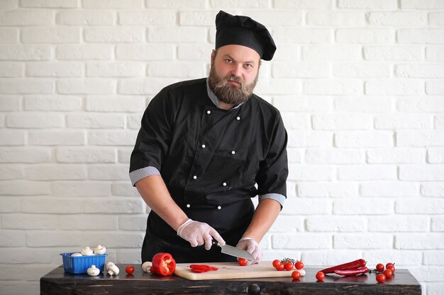 Lo chef barbuto prepara i pasti al tavolo in cucina