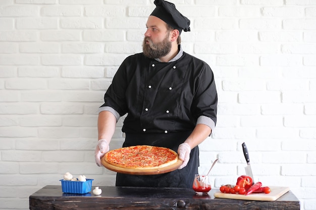 Lo chef barbuto prepara i pasti al tavolo in cucina