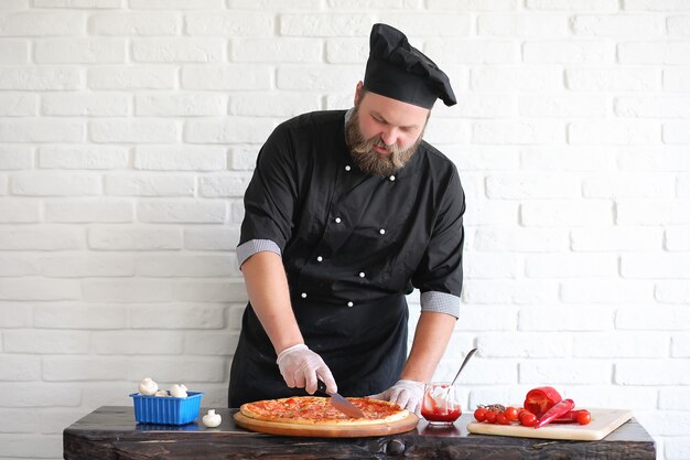 Lo chef chef barbuto prepara i pasti al tavolo in cucina