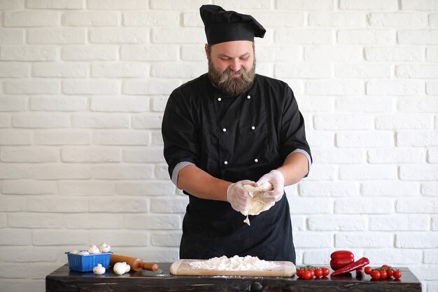 Lo chef chef barbuto prepara i pasti al tavolo in cucina