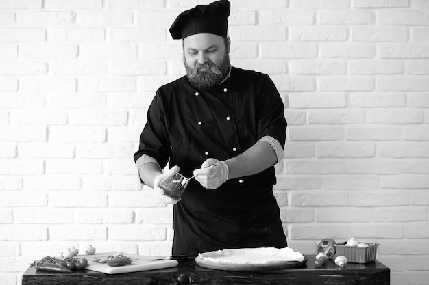 Lo chef chef barbuto prepara i pasti al tavolo in cucina