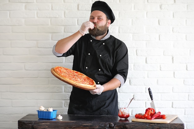 Lo chef chef barbuto prepara i pasti al tavolo in cucina