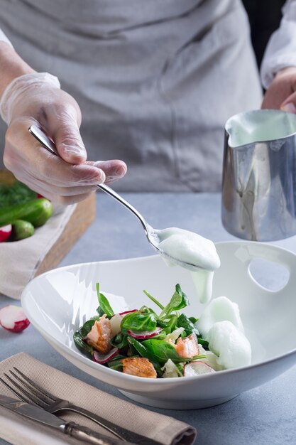 Lo chef completa la cottura dell'insalata e si aggiunge con una salsa bianca al pesce rosso e alle verdure.