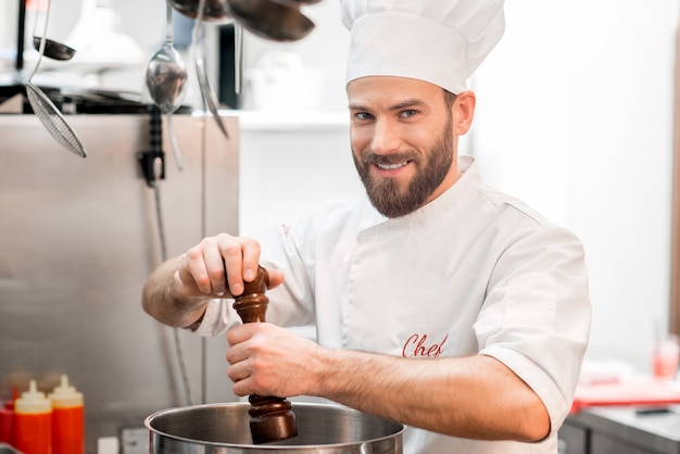 Lo chef cucina in uniforme pepando la zuppa nel grande fornello della cucina del ristorante