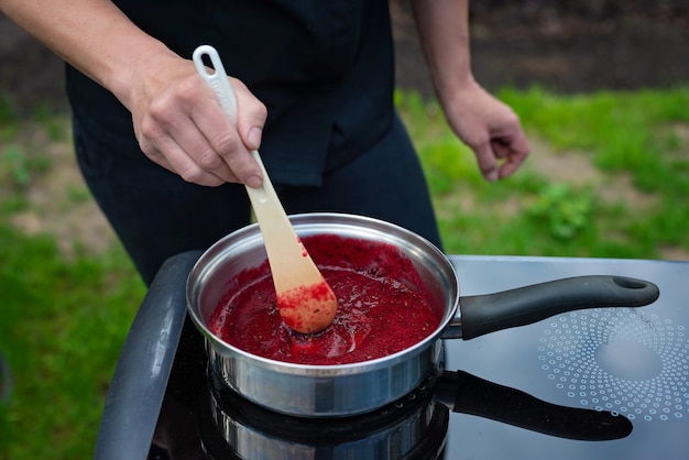 Lo chef cucina purea di bacche per fare la marmellata. Il processo di preparazione della marmellata di bacche.