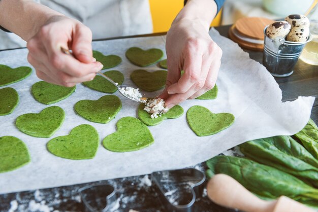 Lo chef cuoco passo dopo passo prepara i ravioli verdi a forma di cuore per una cena festiva