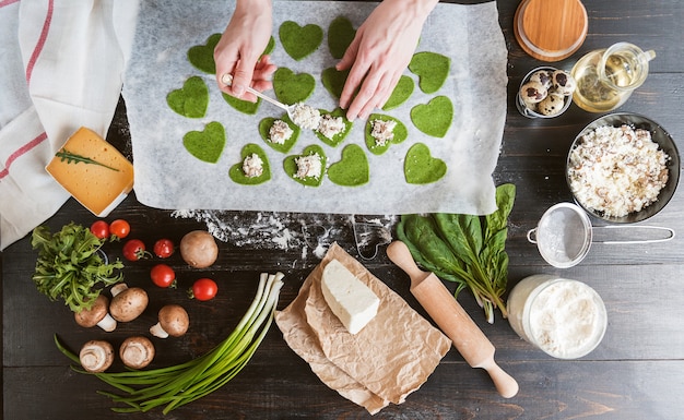 Lo chef cuoco passo dopo passo prepara i ravioli verdi a forma di cuore per una cena festiva