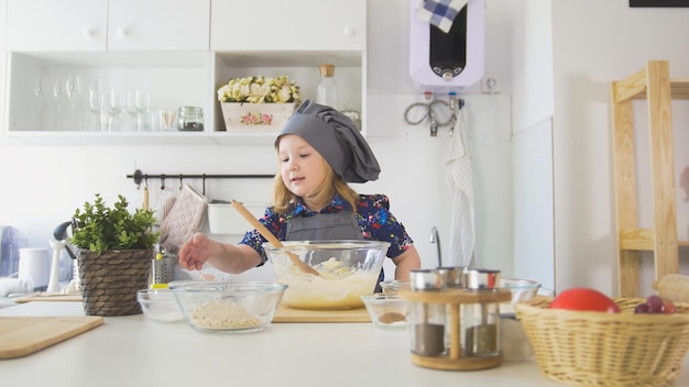 Lo chef della bambina sveglia ha puntato la mano sulle ciotole con gli ingredienti per cucinare in orizzontale