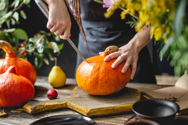 Lo chef donna pulisce una zucca arancione per preparare la cottura