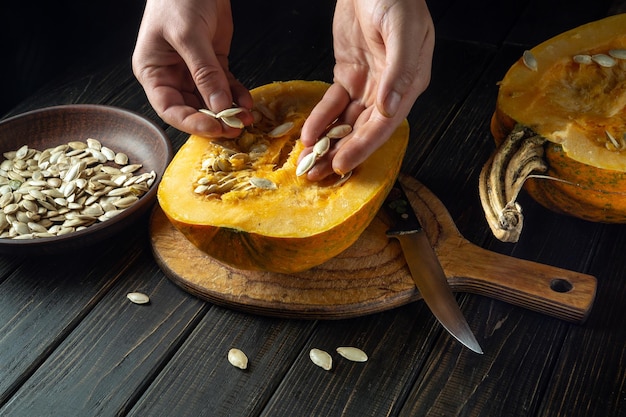 Lo chef estrae i semi dalla zucca per l'uso in cucina Cibo contadino su sfondo nero