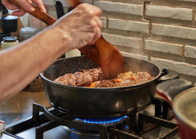 Lo chef frigge gli involtini di carne in una padella su un fornello a gas. Cucina gourmet francese