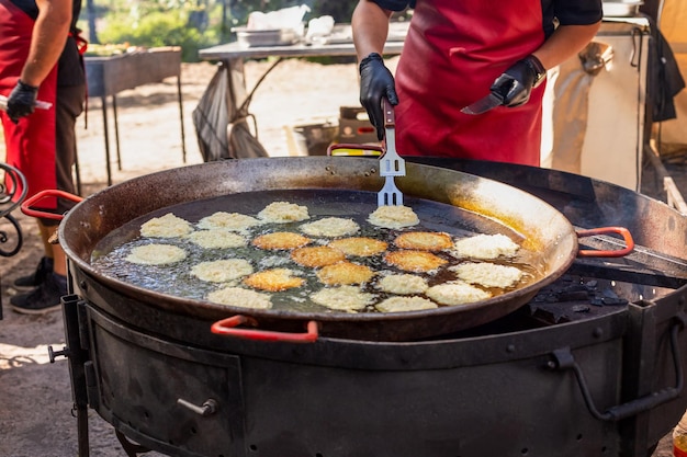 Lo chef frigge le frittelle di patate in una padella capiente