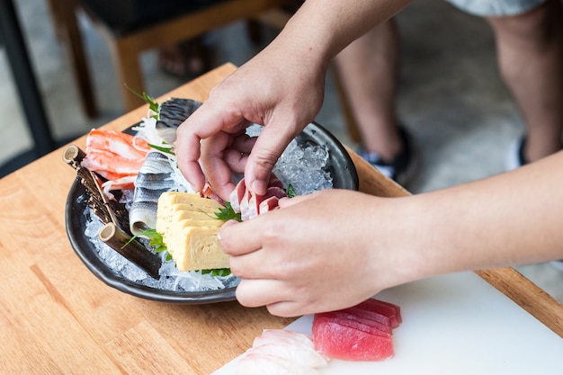 Lo chef giapponese prende il tonno di pesce, salmone sul piatto con ghiaccio