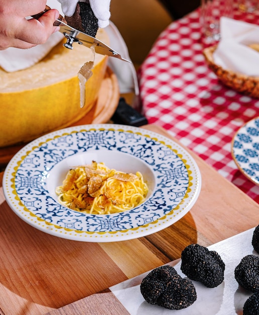 Lo chef gratta le schegge di tartufo sulla pasta con il parmigiano