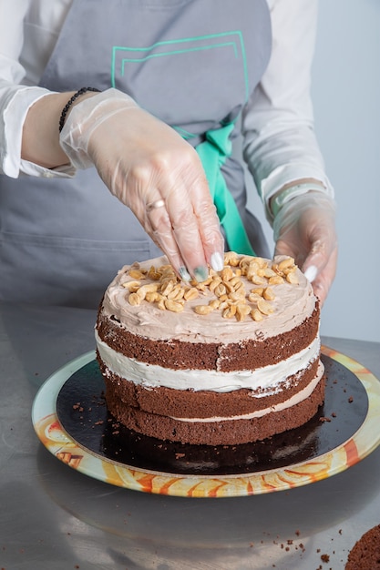 lo chef mani donna cosparge di noci sul terzo strato di torta al cioccolato.