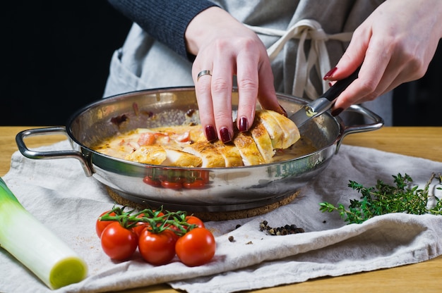 Lo chef mette il petto di pollo tagliato nella padella.