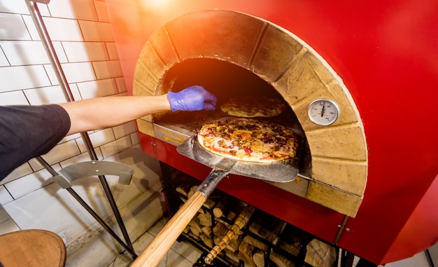 Lo chef mette la pizza cruda nel forno