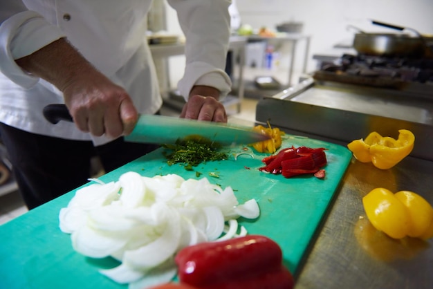 lo chef nella cucina dell'hotel affetta le verdure con il coltello e prepara il cibo