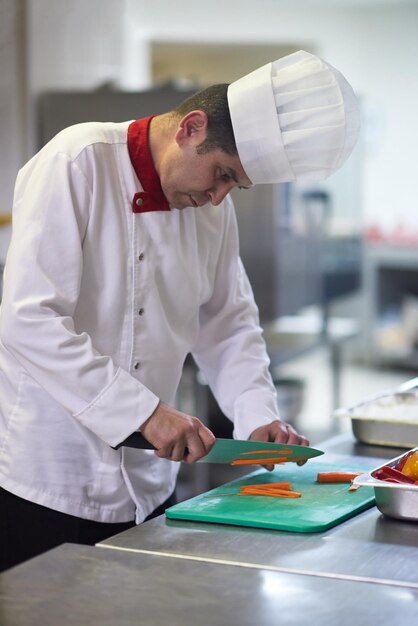 lo chef nella cucina dell'hotel affetta le verdure con il coltello e prepara il cibo