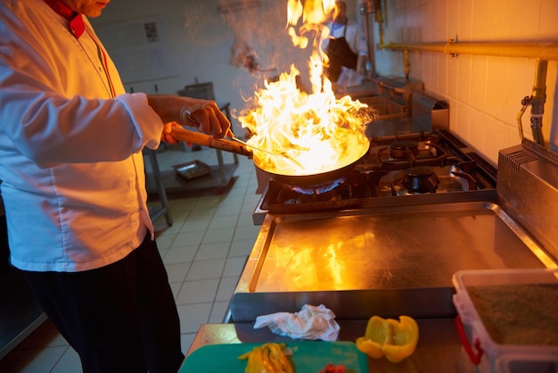 lo chef nella cucina dell'hotel prepara cibo vegetale con il fuoco