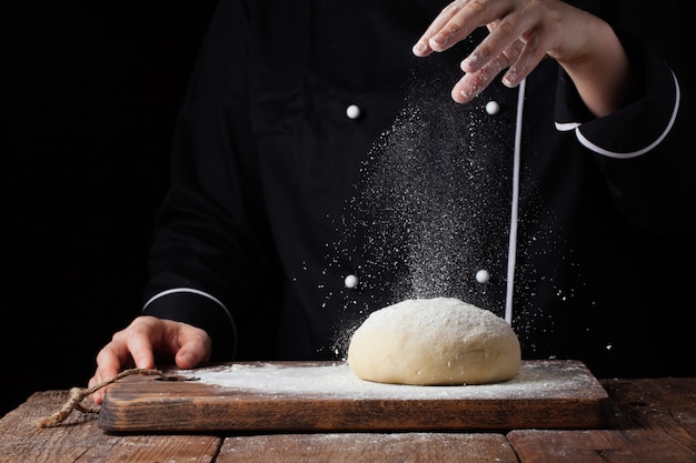 Lo chef passa a versare la farina di farina sulla pasta cruda.