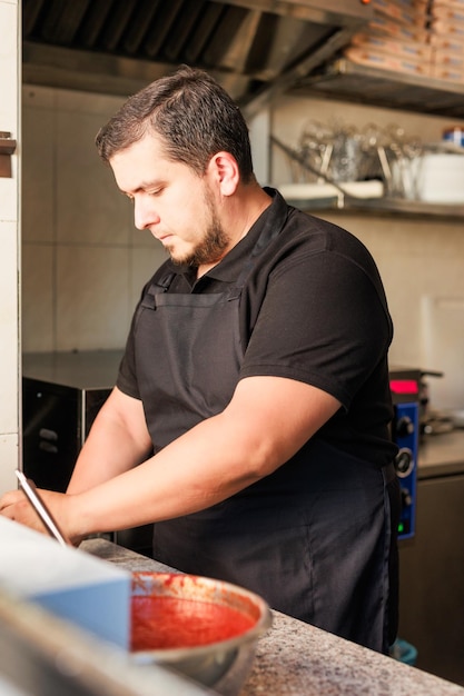 Lo chef pizzeria latino cucina la pizza in uniforme professionale ristorante imprenditore di cucina italiana