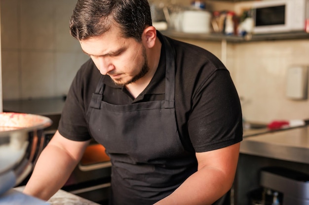 Lo chef pizzeria latino cucina la pizza in uniforme professionale ristorante imprenditore di cucina italiana