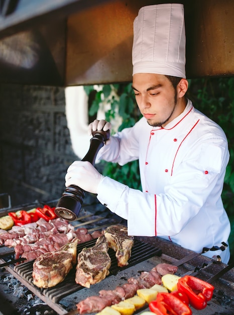 Lo chef prepara carne sul barbecue.