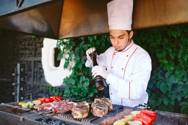 Lo chef prepara carne sul barbecue.