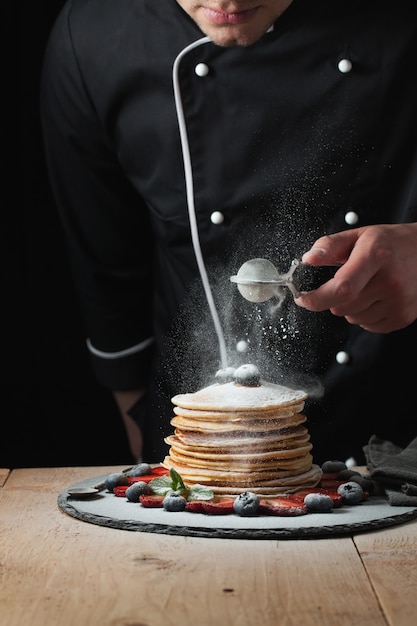 Lo chef prepara frittelle con frutti di bosco.