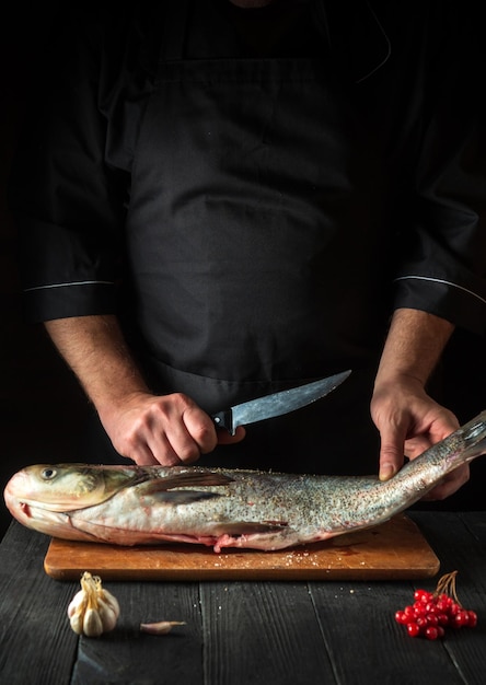 Lo chef prepara l'aringa di carpa argentata in cucina Preparazione per il taglio del pesce con un coltello