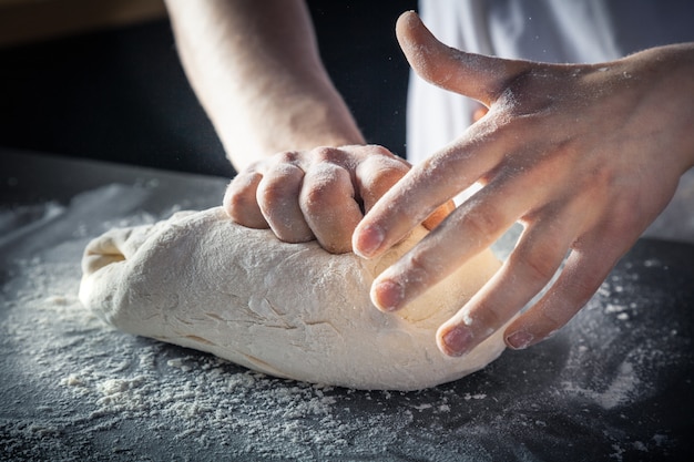 Lo chef prepara l'impasto con la farina. Mani che impastano pasta cruda orizzontale. Copia spazio. Pasta senza glutine per pasta, pasticceria o pizza. Posto di lavoro Baker. Lo chef produce un impasto. Gastronomia, cucina, concetto di panetteria