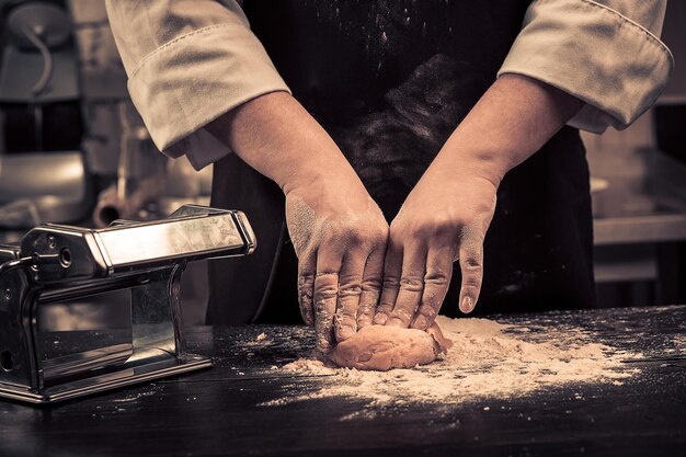 Lo chef prepara l'impasto per la pasta su un tavolo di legno