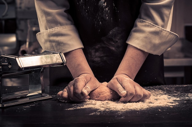 Lo chef prepara l'impasto per la pasta su un tavolo di legno